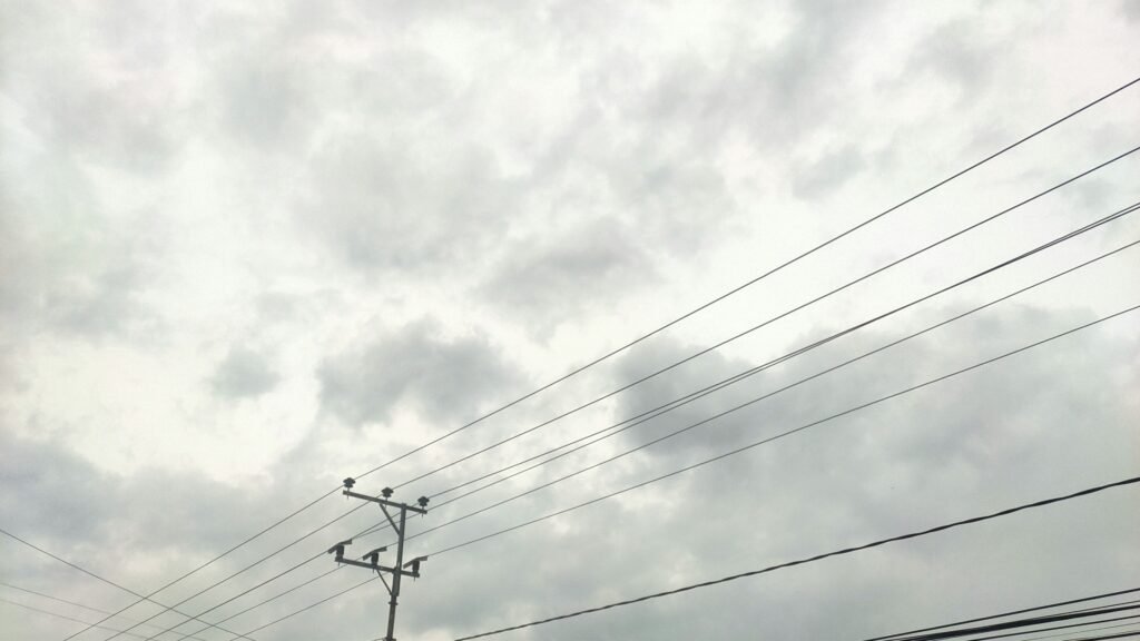 a telephone pole and power lines against a cloudy sky